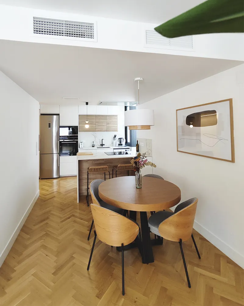 Comedor y cocina integrados, con la mesa redonda de madera