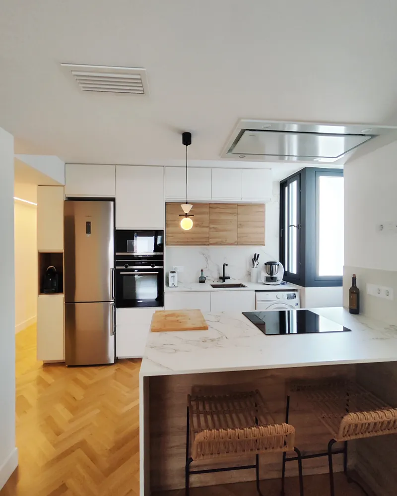 Cocina integrada con la isla y los taburetes de madera
