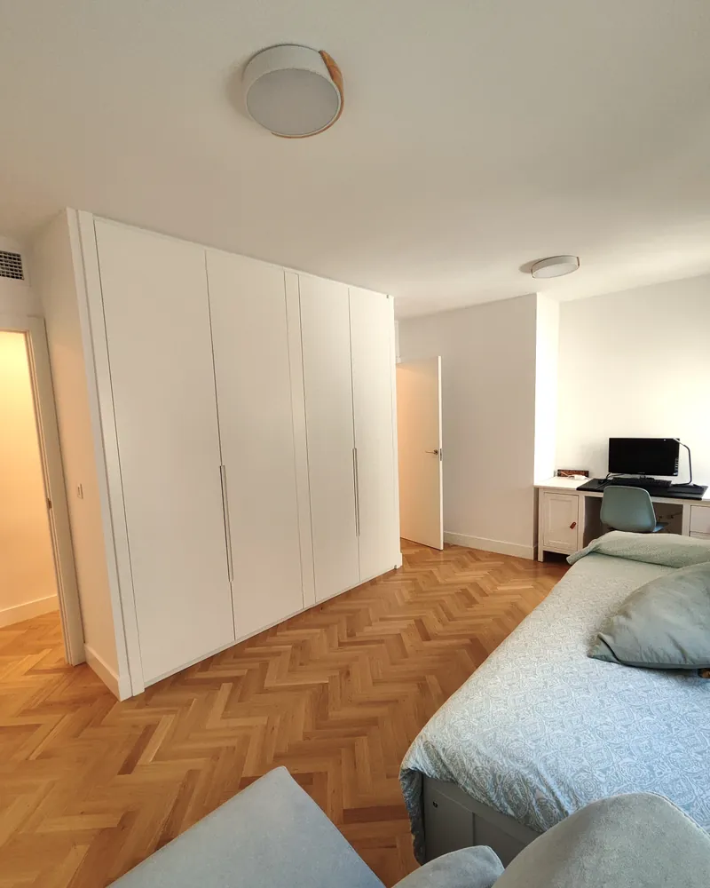 Dormitorio con armarios blancos conectado con el resto de la vivienda