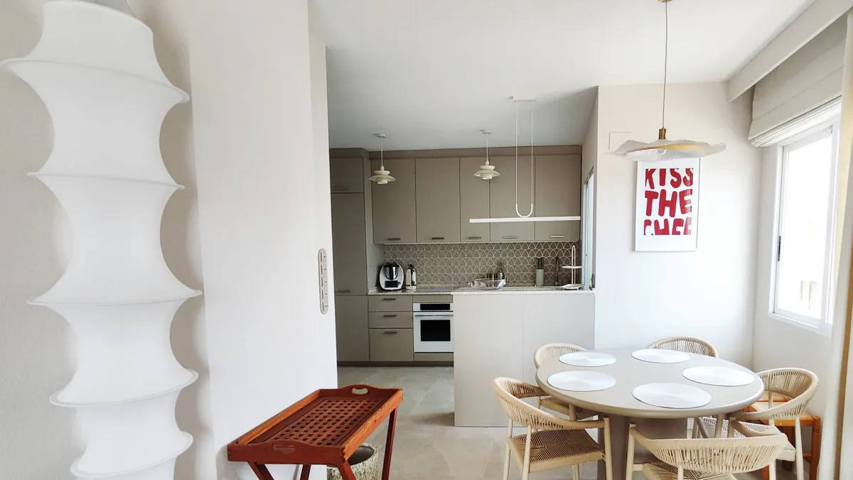 Comedor con la lámpara escultórica blanca y la cocina al fondo