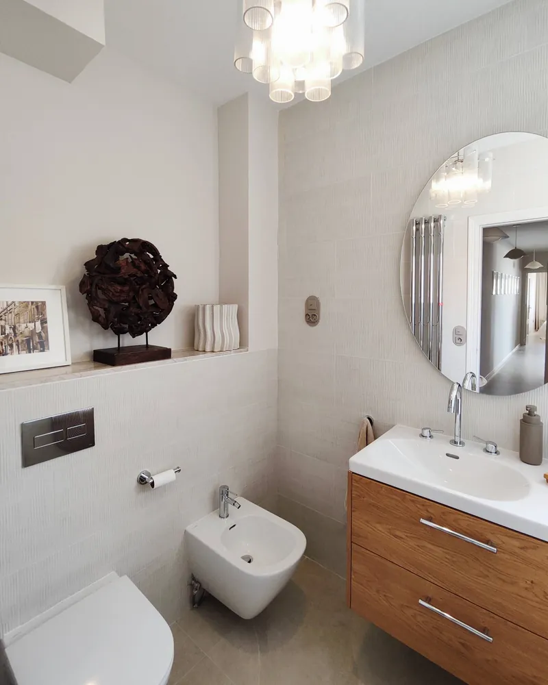 Baño con espejo redondo y lavabo sobre mueble de madera