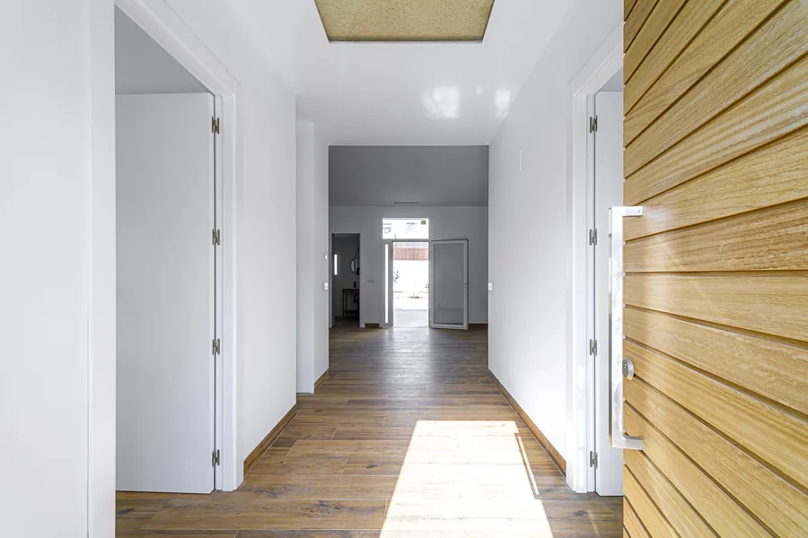 Entrada de la vivienda con el pasillo hacia el patio y el revestimiento de madera