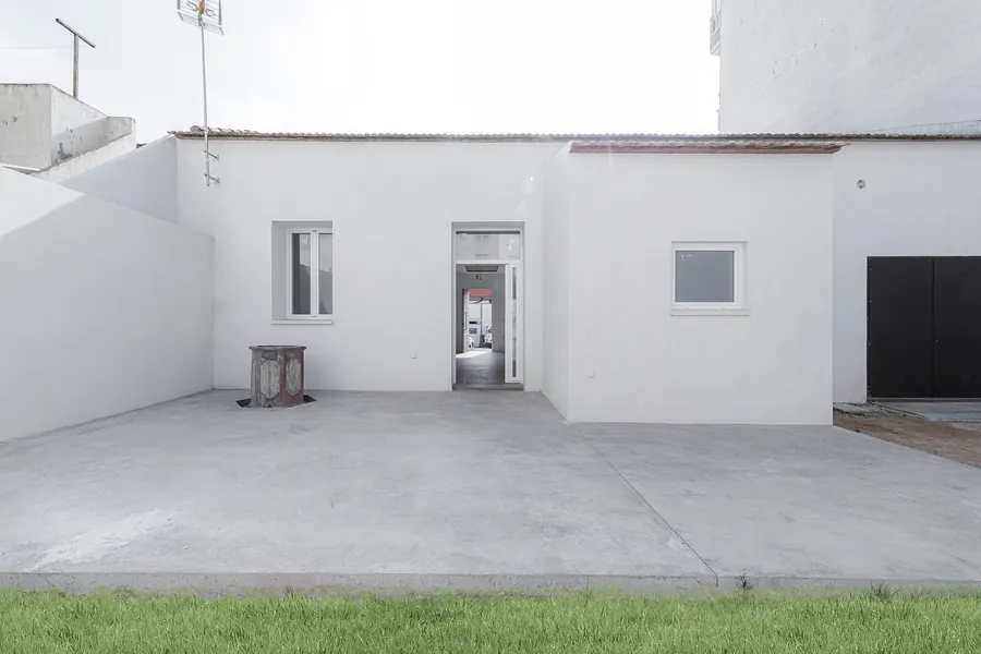 El patio encalado con el pozo original y la fachada trasera de la vivienda